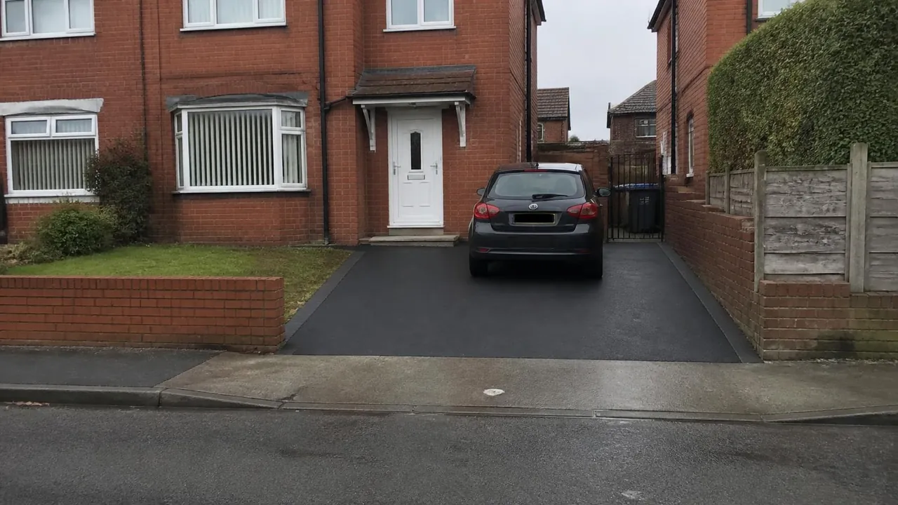 Black tarmac driveway with block edging in front of an ex-council semi